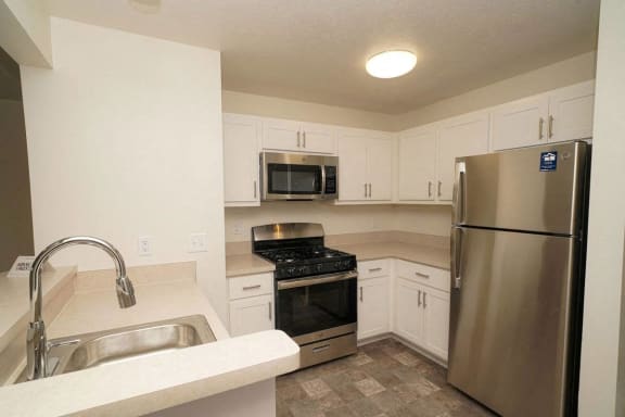 a kitchen with stainless steel appliances and white cabinets  at Arbor Lakes Apartments, Indiana