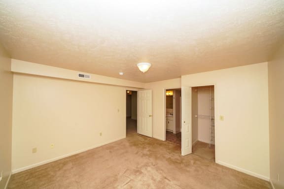 an empty living room with carpet and a hallway to a bathroom at Autumn Lakes Apartments and Townhomes, Mishawaka, 46544