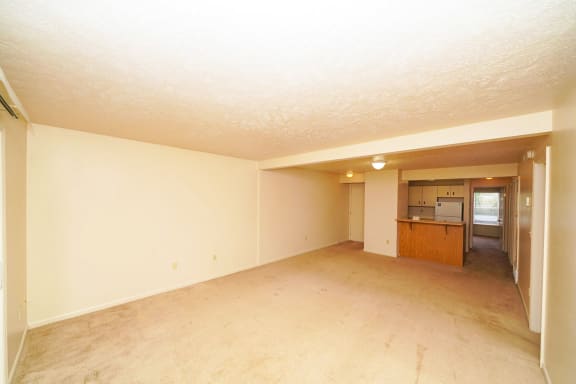 an empty living room with a kitchen in the background at Autumn Lakes Apartments and Townhomes, Mishawaka, IN