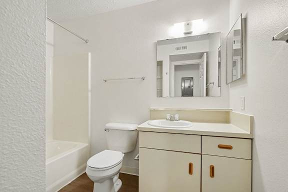 A white bathroom with a toilet, sink, and mirror.