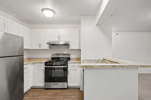 A kitchen with white cabinets and a stainless steel refrigerator.
