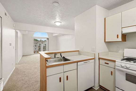A kitchen with white appliances and wooden cabinets.