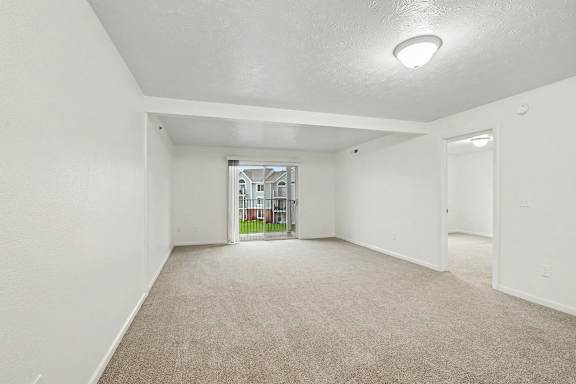 A spacious empty room with carpeted floor and white walls.