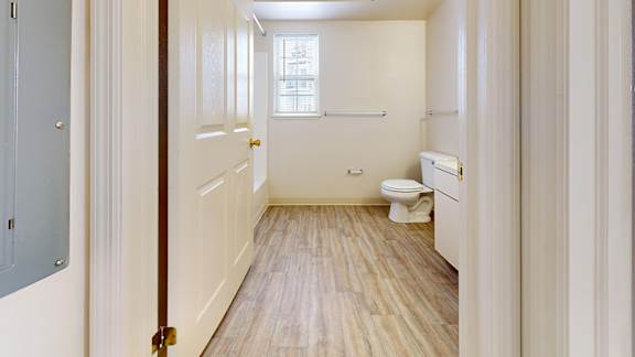 A white bathroom with a toilet, sink, and window.