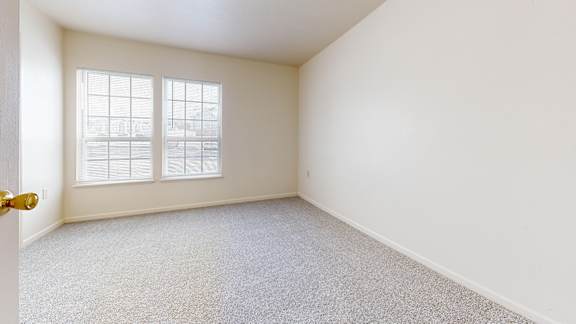 A room with a carpeted floor and a window.