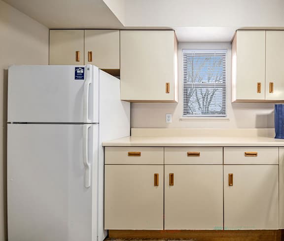 A white refrigerator in a kitchen with beige cabinets.