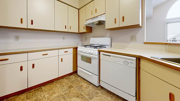 A kitchen with white appliances and wooden cabinets.