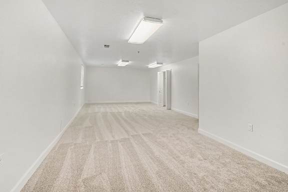 A basement recreation room with carpeted flooring and white walls at Autumn Lakes Apartments and Townhomes in Mishawaka, IN