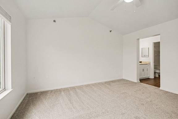 A master bedroom with a cathedral ceiling and a doorway leading to a bathroom and walk-in closet at Autumn Lakes Apartments and Townhomes in Mishawaka, IN