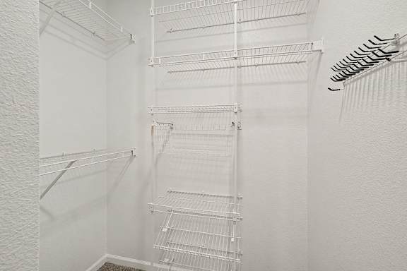 A white walk in closet with shelves and racks at Autumn Lakes Apartments and Townhomes in Mishawaka, IN