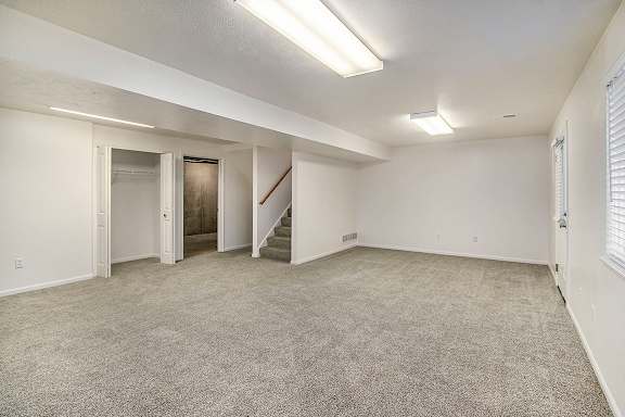 A spacious recreation room with a staircase and a window at Autumn Lakes Apartments and Townhomes, Mishawaka, 46544