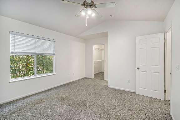 A room with a ceiling fan and carpeted floor.