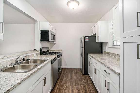 A kitchen with white cabinets and a black refrigerator