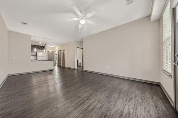 the living room and kitchen of a new home with white walls and wood floors at Avellan Springs Apartments, North Carolina