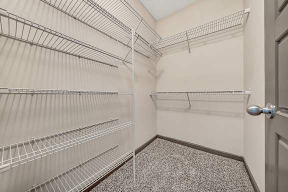 A walk-in closet with metal shelving and a carpeted floor.