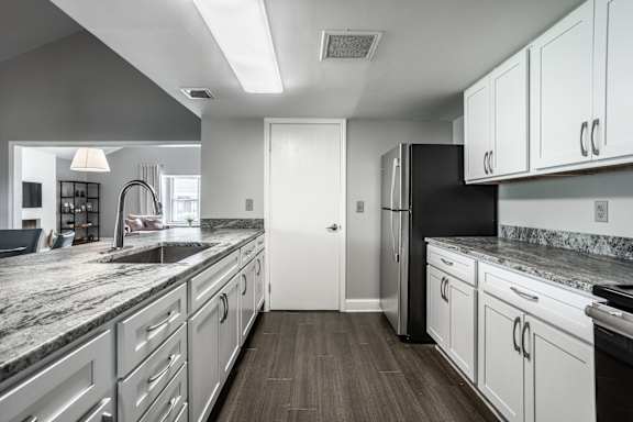 A modern kitchen with white cabinets and a black refrigerator at Bay Pointe Apartments, Lafayette, IN