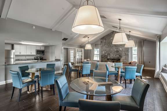 A modern dining room with a glass table surrounded by blue chairs at Bay Pointe Apartments, Lafayette, IN