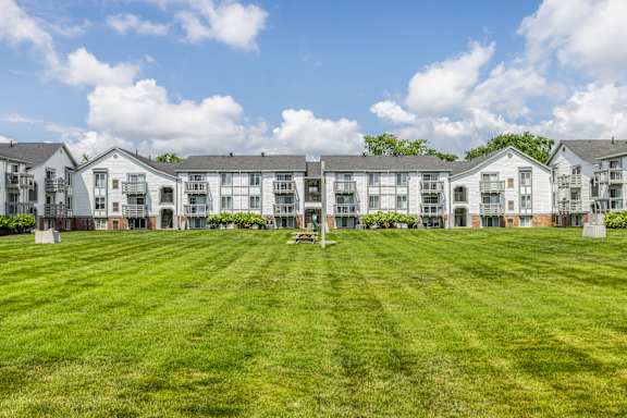 A row of white apartment buildings with green lawns in front at Bay Pointe Apartments, Lafayette, IN
