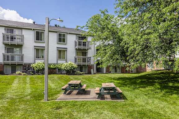 A grassy area with a picnic table in front of a building at Bay Pointe Apartments, Lafayette, IN