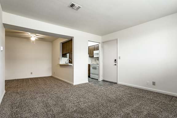 A spacious living area with a kitchenette and a doorway leading to another room at Bay Pointe Apartments, Lafayette