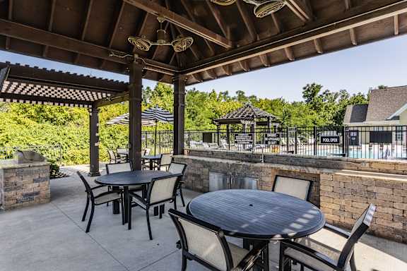 an outdoor patio with tables and chairs and a pool at Bella Vista Apartments, Fishers, IN
