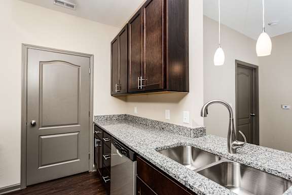 a kitchen with a sink and wooden cabinets and a door at Bella Vista Apartments, Fishers, Indiana