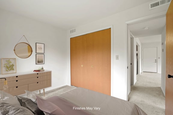 a bedroom with white walls and a wooden wardrobe with a mirror on top of it at Beacon Hill and Great Oaks Apartments, Illinois, 61109