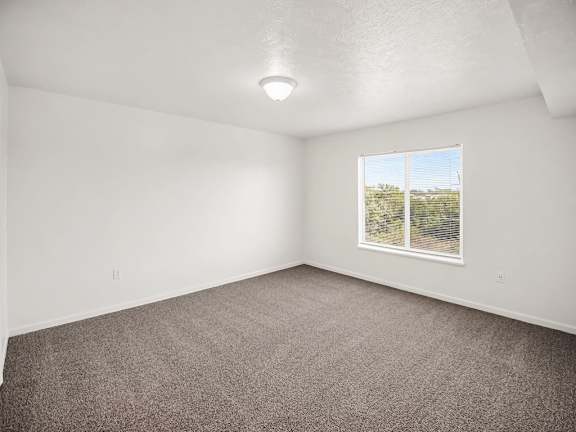 A bedroom with a large window showing a view of trees at Black Sand Apartments Homes, Lincoln, NE 68504