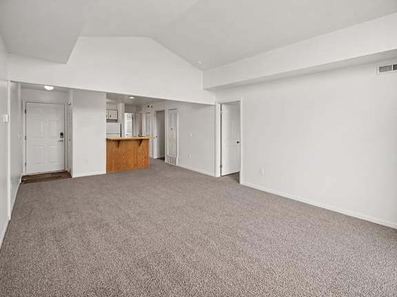 A large, empty living and dining room with a carpeted floor and white walls at Black Sand Apartments Homes, Lincoln, NE 68504