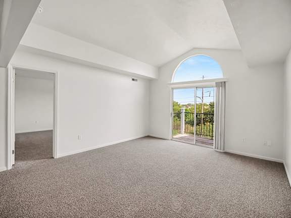 A spacious room with a carpeted floor and a large arched window.