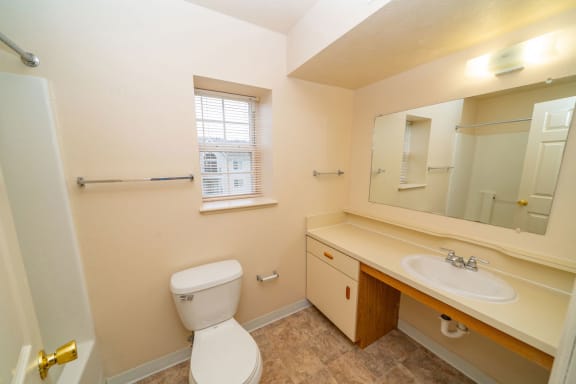 a bathroom with a toilet and a sink and a mirror at Brentwood Park Apartments, Nebraska, 68128