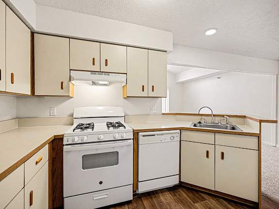 A kitchen with a white stove and dishwasher at Brentwood Park Apartments in LaVista, NE