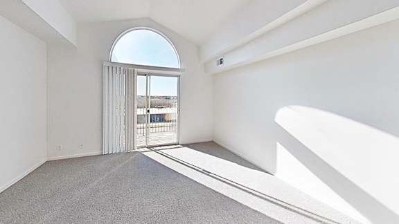 A living room with a large window, cathedral ceiling, and a grey carpet at Brentwood Park Apartments, Nebraska, 68128