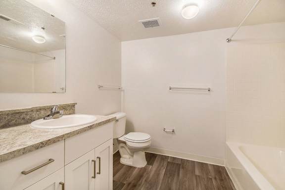 A bathroom with white cabinetry, a sink, toilet, and bathtub at Brentwood Park Apartments in LaVista, NE