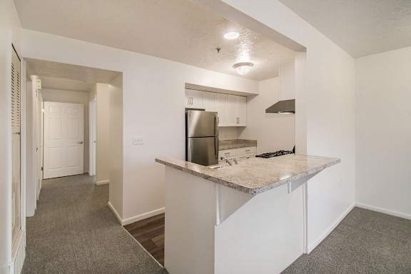 A kitchen with white cabinets, stainless steel appliances and a breakfast bar at Brentwood Park Apartments in LaVista, NE
