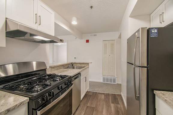 A kitchen with a gas stove and a refrigerator at Brentwood Park Apartments in LaVista, NE