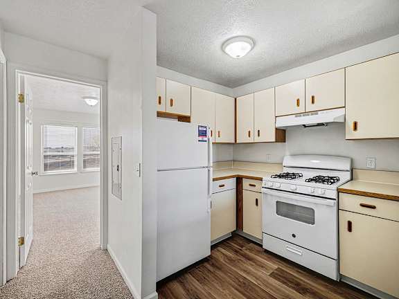 A kitchen with white appliances and wooden cabinets at Brentwood Park Apartments in LaVista, NE