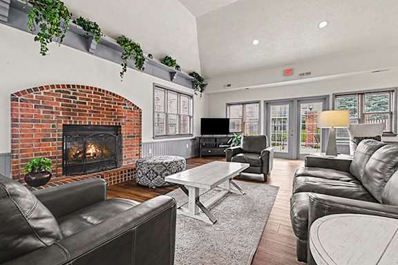 A community room with a fireplace and grey couches at Brentwood Park Apartments in LaVista, NE