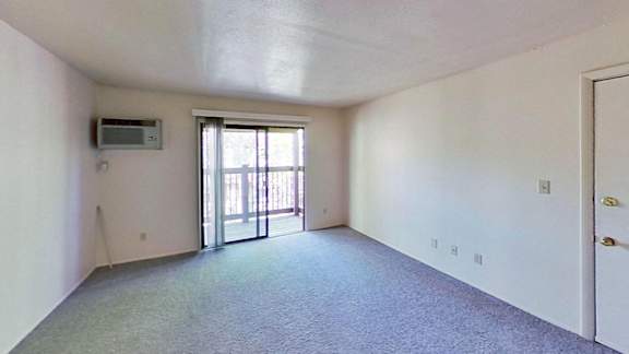 A living room with a carpeted floor and a sliding glass door leading to a balcony A living room with a carpeted floor and a sliding glass door leading to a balcony at Briarwood Apartments in Benton Harbor, MI