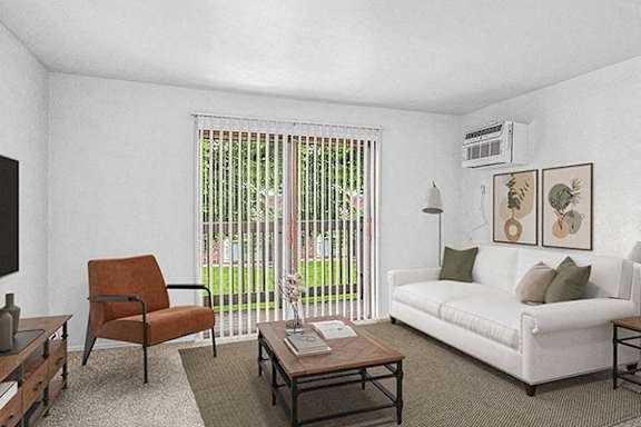 A living room with a white couch, a brown chair, and a slider to a private balcony at Briarwood Apartments, Benton Harbor, MI, 49022