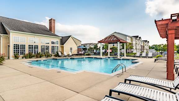 A pool area with sun loungers and a building in the background