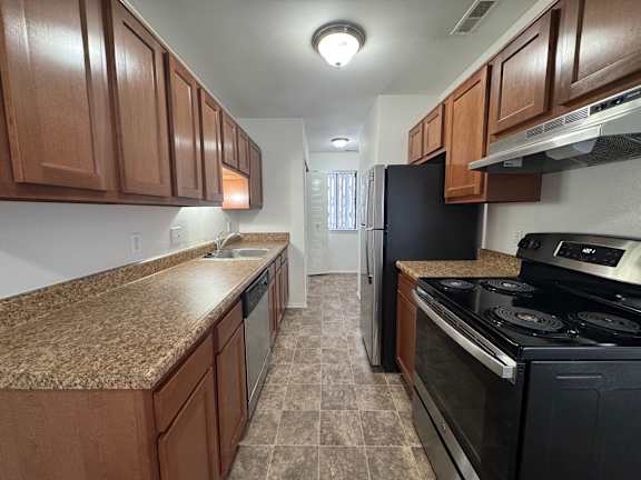 A kitchen with brown cabinets and black appliances.