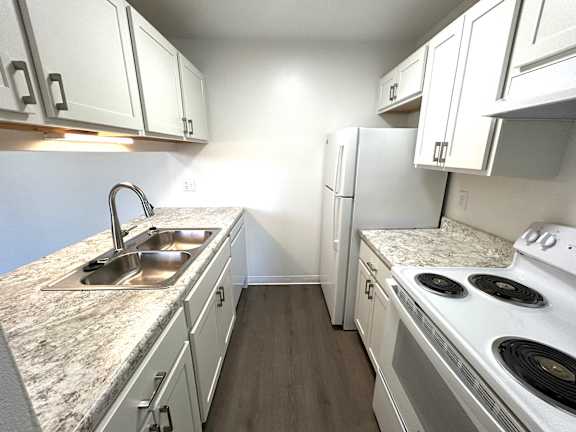 A kitchen with white cabinets and a granite countertop.