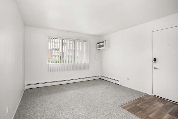 A living room with a window and plush carpet at Brookside Apartments, Springfield