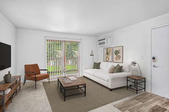 A living room with a white couch, a brown chair, and a coffee table at Brookside Apartments, Springfield