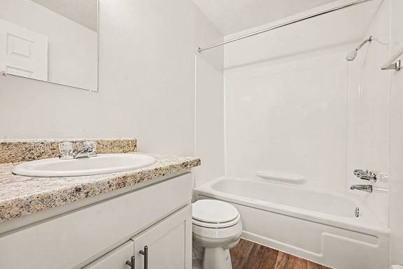 A white bathroom with a sink, toilet, and bathtub.