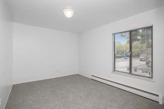 A bedroom with a large window and a grey carpet at Brookside Apartments, Springfield