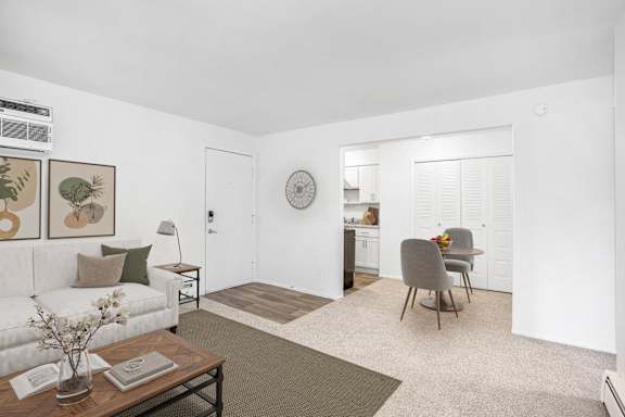 A living and dining room with a couch, a chair, a table, and a clock on the wall at Brookside Apartments, Springfield