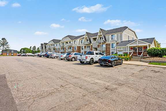 A parking lot with cars and apartment buildings in the background at Brookside Apartments in Springfield, MI