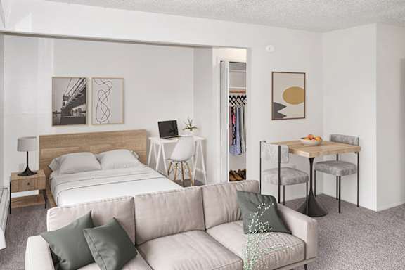 A sleeping area with a bed and a living room with a couch, a chair, and a table at Brookside Apartments, Springfield and a clothing rack.